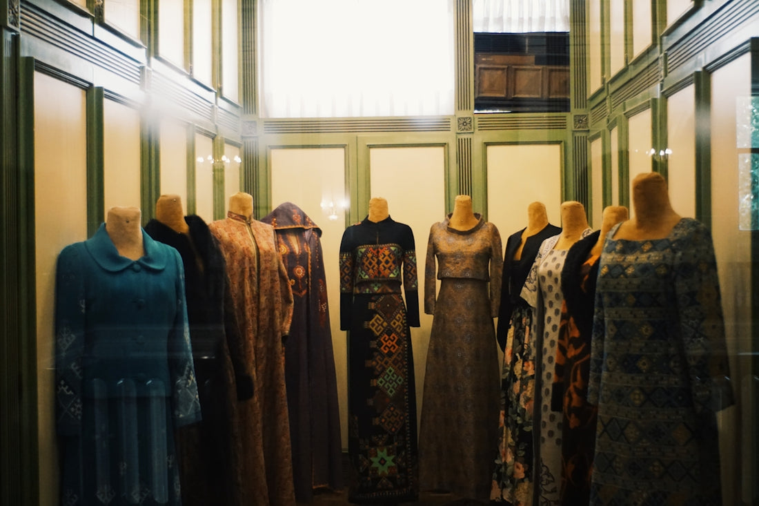Mannequins display vintage dresses in a museum hall.